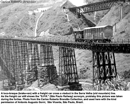 A loco-breque (brake-van) with a freight car cross a viaduct in the Serra Velha (old mountain) line.