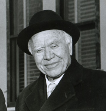 Lord Beaverbrook smiling in a black hat