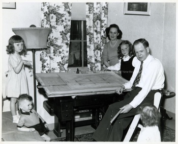 One of the veteran students living at Alexander College attempts to finish his drafting assignment while surrounded by his growing family. Note the improvised drafting table made out of his wife's sewing machine, 1947. UA PC 9; no. 25 (5).