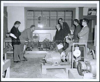 Walter Smolinski, James Dineen, Baird, R. J. Collyer, Doug Rogers, Bob Scott, and Bob Burridge examine the new power laboratory from the Electrical Engineering department. Record group/Fonds Acc. 2010.05; Series 1; Item no. 238, File 10 1957.