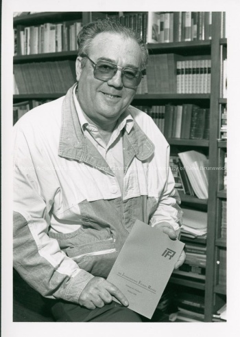 The International Fiction Review editor Saad Elkhadem sitting holding an issue of the journal, September 1989. PR; Series 2; Sub-series 2; File 302; Item 1.