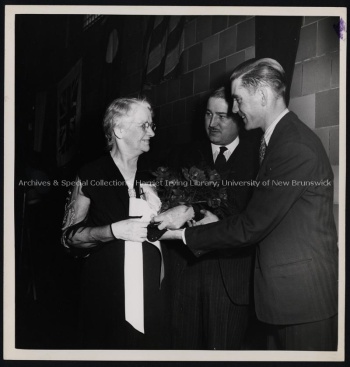 Margaret (Baird) Jones being presented with flowers at Encaenia by J. Richard Petrie and Jack Murray, (1941?). UA PC 4; no. 16 (14). Photo credit: The Standard.