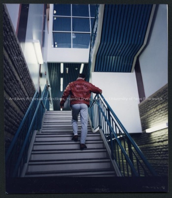 Unidentified male climbing steps inside Oland Hall wearing a UNB jacket Record group/Fonds PR; Series 2; Sub-series 1; File 135; Item 1 October 1989